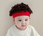 Bonnet perruque à cheveux bouclés bruns et bandeau rouge sur la tête pour bébé.