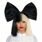 Femme portant une perruque Lady Gaga noire et blanche cheveux lisses avec un gros nœud papillon noir sur la tête.